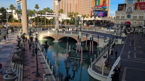 Las-Vegas-USA,-Venetian-Lake-With-Gondola,-People-and-Strip-Traffic-on-Sunny-Day