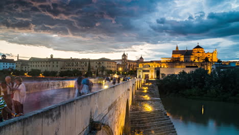 Zeitrafferaufnahmen-Von-Tag-Und-Nacht,-Die-Touristen-Zeigen,-Die-über-Die-Römische-Brücke-In-Córdoba,-Spanien-Gehen