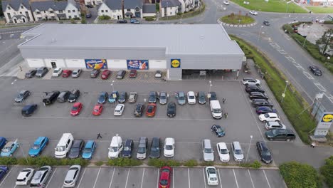 Aerial-establishing-shot-of-a-Lidl-supermarket-in-Bude,-Cornwall,-United-Kingdom,-in-July-2024,-featuring-the-supermarket-building,-car-park,-and-surrounding-roads