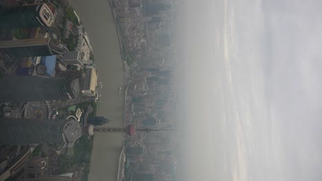 Panning-shot-over-Lujiazui-financial-district-covered-with-smog-from-Shanghai-Tower's-lookout-in-Pudong,-China