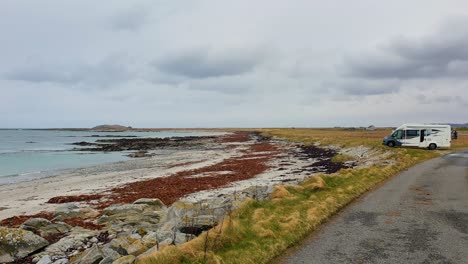 Tourism-campervan-parked-on-coastline-overlooking-ocean-on-the-remote-island-of-Outer-Hebrides-in-Scotland-UK