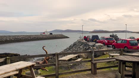 Rows-of-parked-vehicles-awaiting-the-arrival-of-Caledonian-MacBrayne-inter-island-ferry-on-remote-island-in-Outer-Hebrides-of-Scotland-UK