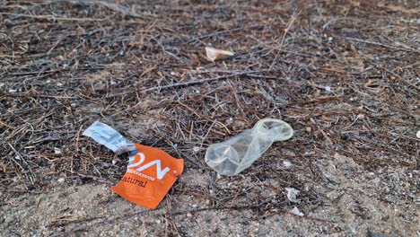 Close-up-of-a-used-condom-lying-on-the-ground-next-to-its-container