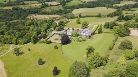 Aerial-view-of-Grade-Two-Star-listed-Hayne-Manor-surrounded-by-lush-green-countryside-in-Devon,-England,-June-2024