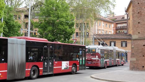 Public-transportation,-articulated-trolleybus-and-bus-of-Tper-company-in-Bologna,-Italy-near-brick-gates