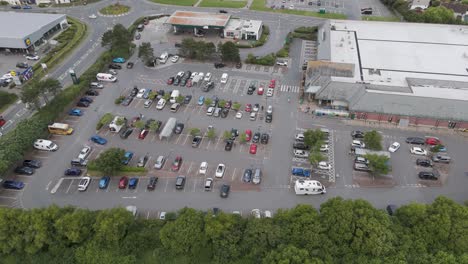 Aerial-orbital-view-of-Morrisons-supermarket-and-large-carpark,-showcasing-surrounding-infrastructure,-Bude,-Cornwall,-UK,-July-2024