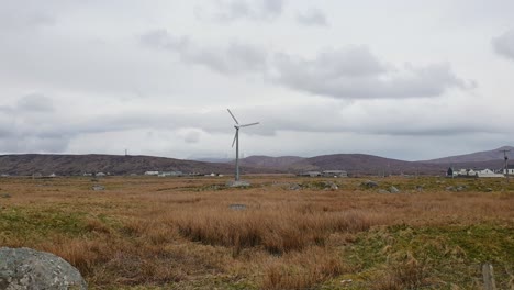 Energy-wind-turbine-spinning-in-rural-countryside-farmland-of-remote-Outer-Hebrides-in-Scotland-UK