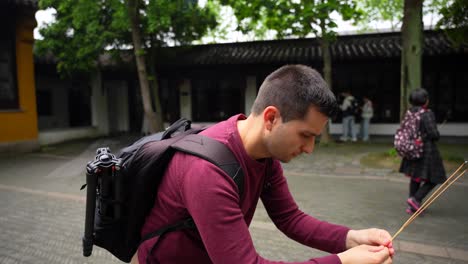 Tourist-Mann-Verneigt-Sich-Im-Gebet-Mit-Drei-Räucherstäbchen-In-Einem-Chinesischen-Buddhistischen-Tempel-In-Suzhou,-China