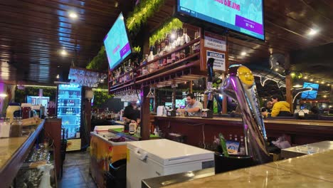 Timelapse-of-evening-life-of-a-vivid-bar-from-the-counter,-as-the-bartender-serves-the-guests-and-pours-beer-in-Quepos,-Costa-Rica