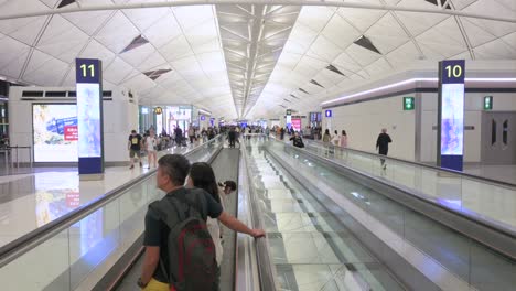 Los-Pasajeros-Del-Vuelo-Son-Vistos-En-Una-Escalera-Mecánica-Horizontal-En-Movimiento-Dirigiéndose-A-Sus-Puertas-En-La-Terminal-De-Salidas-Del-Aeropuerto-Internacional-Chek-Lap-Kok-De-Hong-Kong.