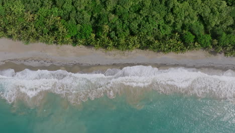 Top-down-aerial-of-the-ocean-waves-washing-up-against-the-beach-in-Patillas,-Puerto-Rico