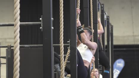 Slow-motion-shot-of-a-female-crossfit-athlete-climbing-up-a-rope-to-finish