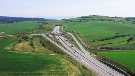 Drone-shot-of-European-route-E50-highway-through-green-agricultural-fields-landscape-connecting-European-continent,-Levoca