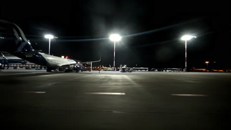 Athens-airport-at-night,-planes-standing-on-the-gates-and-bright-light-is-shining,-dark-sky,-slow-motion-and-copy-space