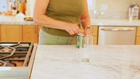 An-adult-woman-pouring-soda-into-a-drinking-glass-in-a-modern-kitchen