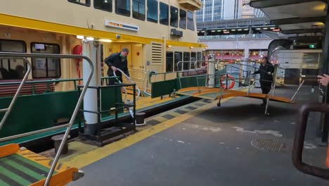 Wharf-workers-moving-a-boarding-walkway-and-releasing-and-storing-the-mooring-line-at-Circular-Quay