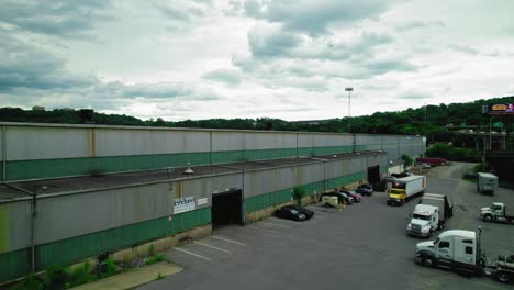 A-flatbed-semi-truck-waiting-to-get-loaded-outside-an-industrial-warehouse-in-Pittsburgh,-Pennsylvania-on-a-cloudy-day