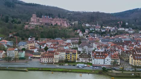 Vista-Aérea-Paralela-De-Drones-Panorámica-A-La-Izquierda-De-La-Ciudad-Del-Castillo-De-Heidelberg,-Baden-württemberg,-Alemania-Con-Casas-Coloridas,-Calles-Y-Automóviles