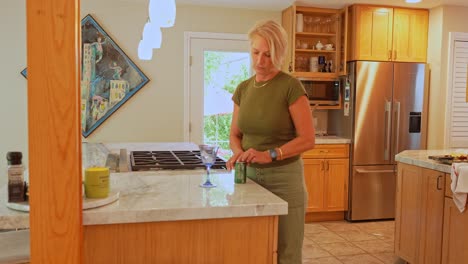 An-adult-woman-pouring-soda-into-a-dinner-glass-in-a-modern-kitchen