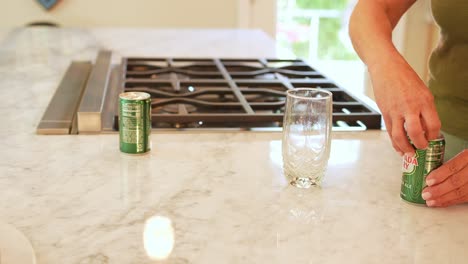 An-adult-woman-pouring-soda-into-a-glass-in-a-modern-kitchen