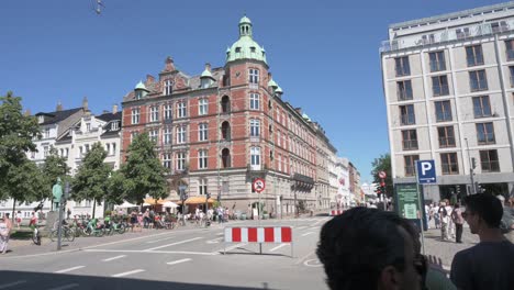 Blick-Auf-Einen-Stadtplatz-In-Kopenhagen,-An-Dem-Ein-Roter-Bus-Vorbeifährt.-Überall-Auf-Dem-Platz-Sind-Viele-Menschen-Und-Es-Wimmelt-Von-Touristen.