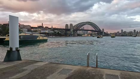 Mehrere-Fähren-Fahren-In-Richtung-Der-Anlegestellen-Am-Circular-Quay-Mit-Dem-Sydney-Opera-House-Und-Der-Brücke-Dahinter-Am-Frühen-Abend