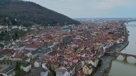 Aerial-pan-left-drone-view-of-Heidelberg,-Baden-Württemberg,-Germany-with-colorful-houses,-street,-roofs,-bridge-and-cars