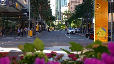 Urban-street-scene-capturing-traffics-at-the-intersection-between-Edward-and-Queen-street-at-central-business-district,-downtown-Brisbane-city,-with-towering-skyscrapers-on-both-sides,-slow-motion