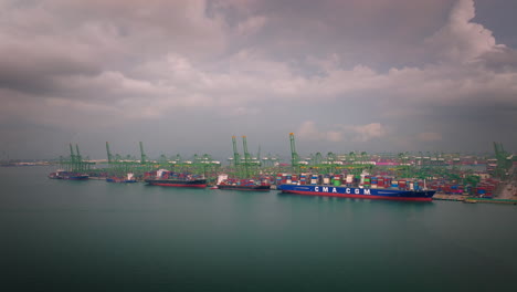 Drone-view-at-Port-of-Singapore-of-container-ships,-cranes-and-containers