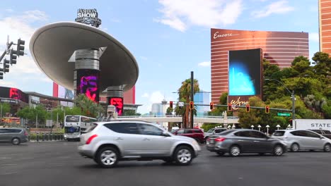 POV-Straßenansicht-Des-Verkehrs,-Der-Tagsüber-Eine-Kreuzung-Auf-Dem-Las-Vegas-Boulevard-überquert,-Im-Hintergrund-Die-Hotels-Wynn-Und-Encore