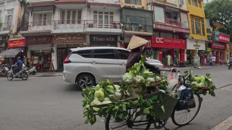 Street-vegetable-vendor-on-bicycle-walk-on-the-side-of-Hanoi-busy-road