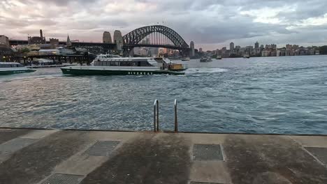 Sydney-Ferries-Manövrieren-Am-Circular-Quay-Mit-Dem-Opernhaus-Und-Der-Harbour-Bridge-Dahinter-Am-Frühen-Abend