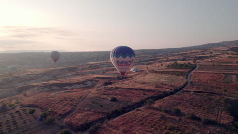 Aerial-view-of-hot-air-balloons-and-sunrise-glare-over-Uchisar,-Cappadocia