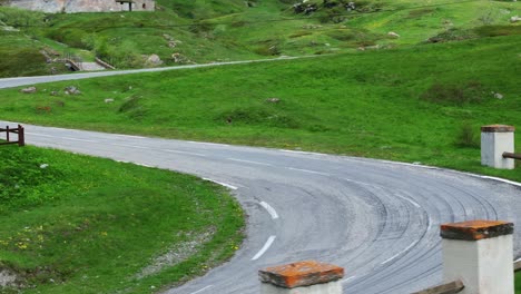 Aerial-shot-of-black-car-driving-up-winding-road-through-French-countryside