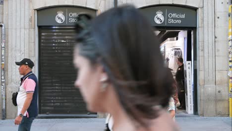 Pedestrians-walk-past-Real-Madrid's-official-store-in-Madrid,-Spain