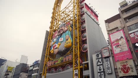 A-smooth-gimbal-shot-of-the-Don-Quijote-building-in-Dotonbori,-Osaka,-moving-from-right-to-left-across-the-river