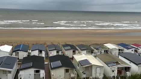 Aerial-top-down-of-solar-panels-on-mobile-homes-on-sandy-beach-in-front-of-north-sea,-Netherlands