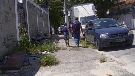 Young-boy-holding-his-mother's-hand-while-walking-in-the-street-on-a-hot-summer-day