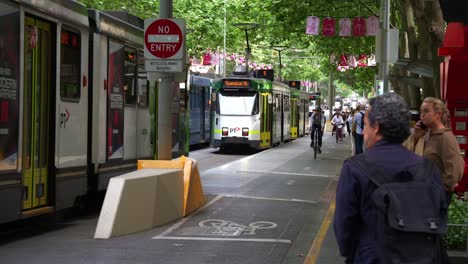 Swarms-of-cyclists-ride-in-their-dedicated-bike-lane,-alongside-the-tram-tracks-where-trams-rumble-along,-in-Melbourne's-city,-highlighting-the-city's-the-vibrant-and-green-urban-environment