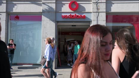 People-walk-past-the-Vodafone-store,-a-British-multinational-telecommunications-corporation,-in-Spain