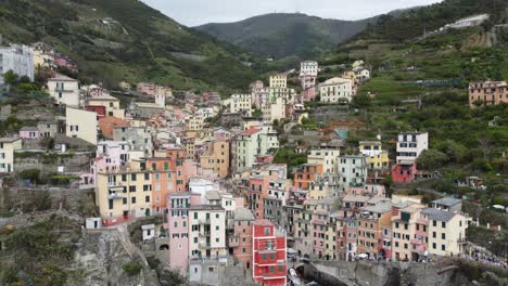 Aerial-ascent-revealing-colorful-houses-built-on-uneven-slopes-in-Riomaggiore,-Italy