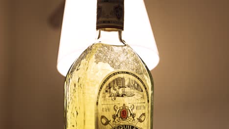 bottle-of-Fortaleza-Los-Abuelos-Reposado-backlit-by-a-warm-lamp-swirling-air-bubbles-inside-BOTTOM-TO-TOP