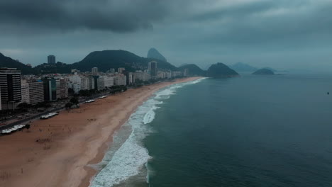 Dramatische-Luftaufnahmen-Von-Rio-De-Janeiro,-Brasilien,-Die-Das-Meer,-Den-Strand-Und-Die-Stadt-Unter-Stimmungsvollem,-Bewölktem-Himmel-In-Einem-Dunklen-Kinostil-Zeigen