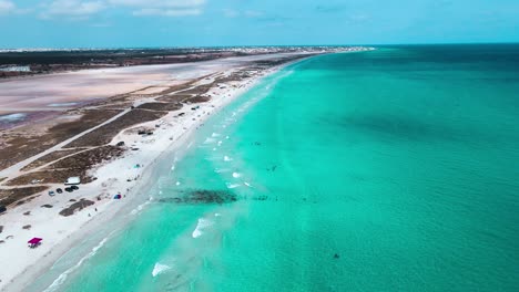 The-image-is-an-aerial-view-of-a-beach-with-crystal-blue-water-at-Mahdia,-where-people-are-enjoying-various-activities