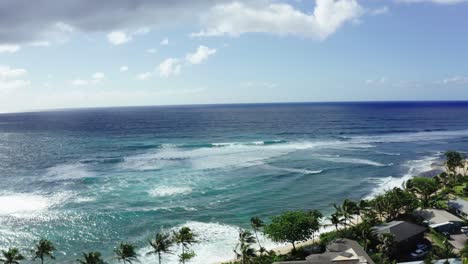 Drone-shot-of-waves-rolling-into-Oahu's-shoreline-on-a-sunny-day