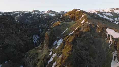 Aerial-landscape-view-of-Icelandic-mountain-peaks-with-melting-snow,-at-dusk