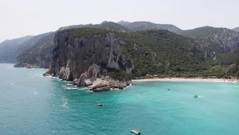 Barcos-En-Cala-Sixtine,-Hermosa-Playa-Con-Acantilados-En-La-Costa-De-Cerdeña