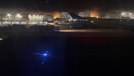 Frankfurt-Airport-at-night-filmed-through-the-window-of-a-landing-airplane-with-passenger-busses-passing-by