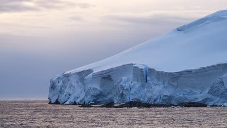 Glaciar-Al-Atardecer-Y-Océano-En-La-Costa-De-La-Antártida,-Paisaje-Invernal-De-Hielo-Y-Costa,-Paisaje-Glaciar-Helado-Con-Un-Gran-Glaciar-Junto-Al-Mar-En-La-Península-De-La-Antártida-Con-Cielo-Naranja