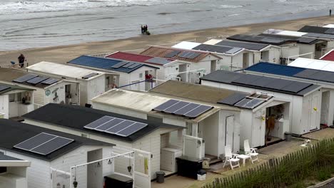 Walking-tourist-at-beach-of-Zandvoort-with-mobile-home-buildings-and-solar-panels-on-roof